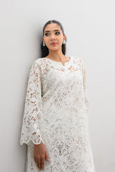 Woman wearing a white lace dress against a plain background