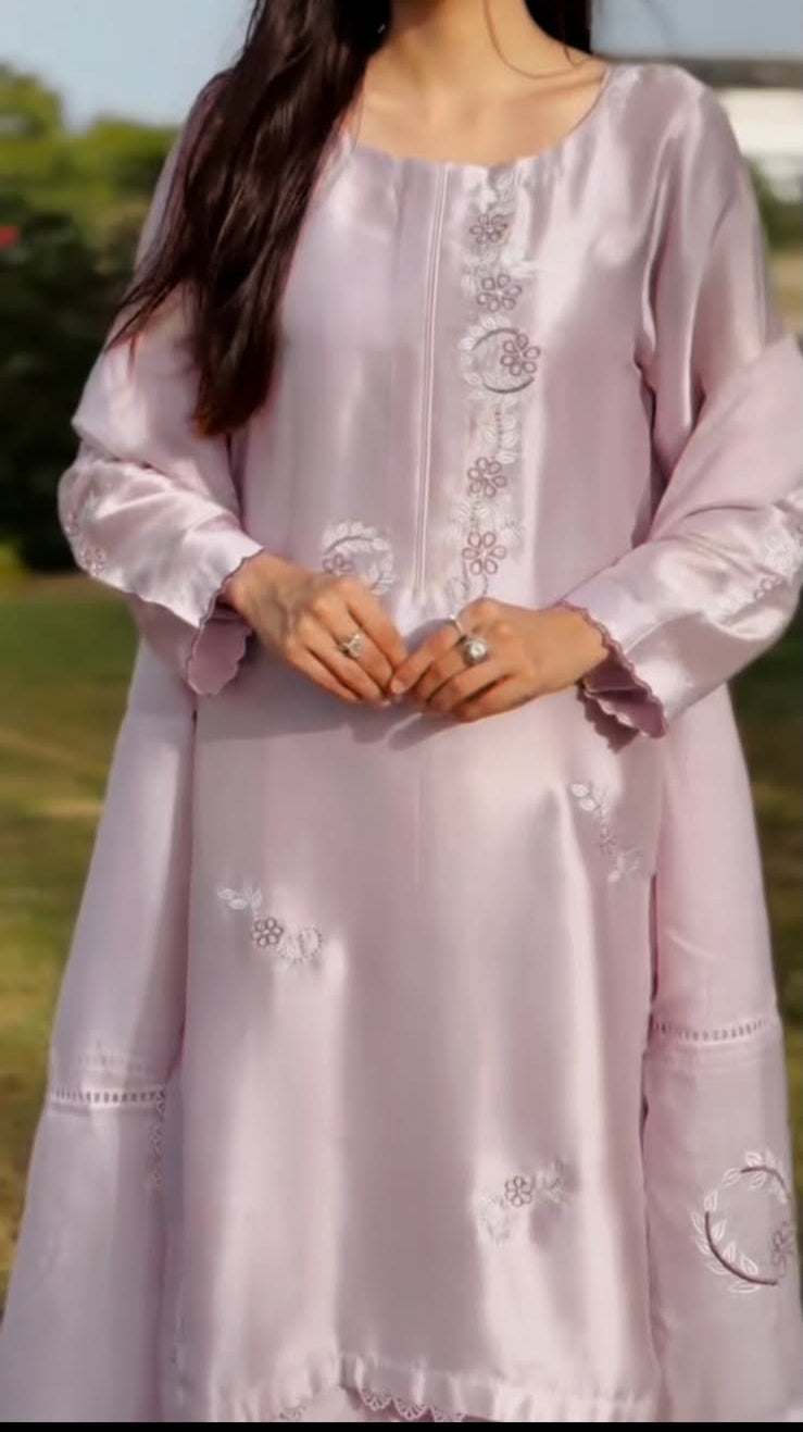 Woman wearing a lilac traditional outfit with intricate designs outdoors.